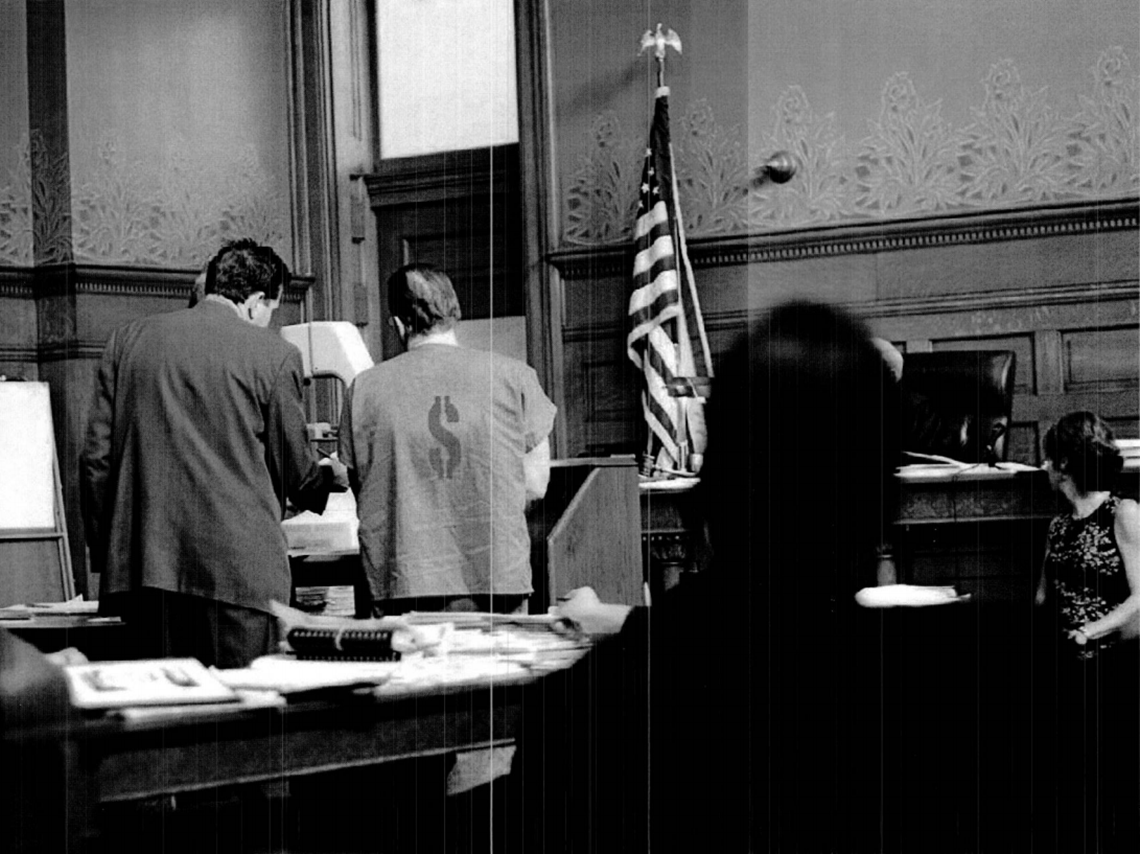 Photo of courtroom with a defendant consulting with an attorney